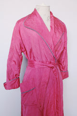 Women's vintage 1950's Lyn Delle label long sleeve long length bright pink quilted robe jacket with teal colored trim.