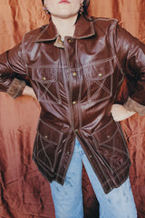 Women's or men 's vintage 1970's Montgomery Ward label long sleeve chocolate brown colored leather jacket with contrast stitching and popper buttons.
