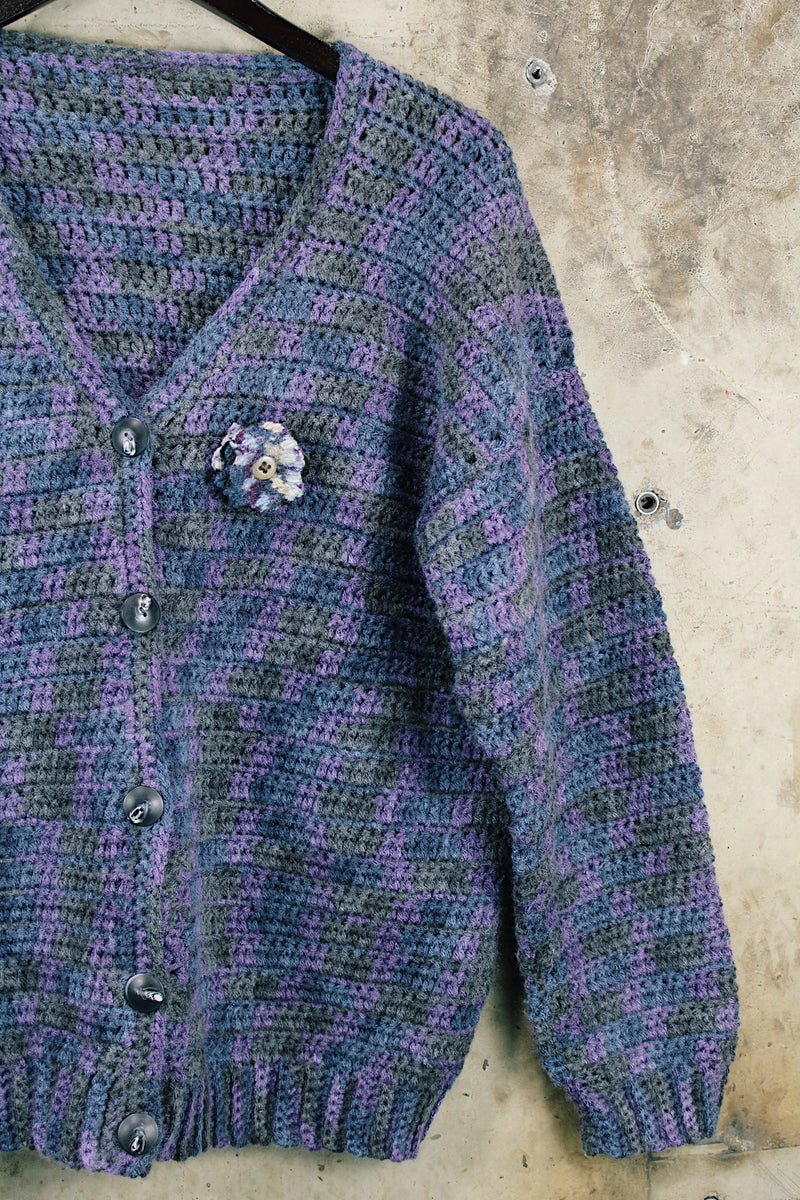 Women's vintage 1990's long sleeve acrylic knit button up cardigan in purple and blue colors with a flower pin.