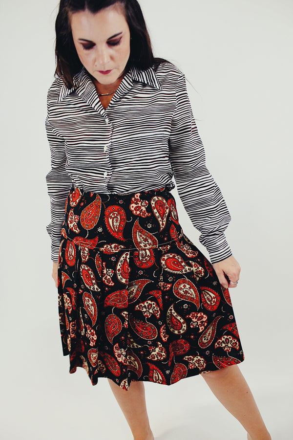 Knee length pleated skirt in forest green, red, and white paisley print front 