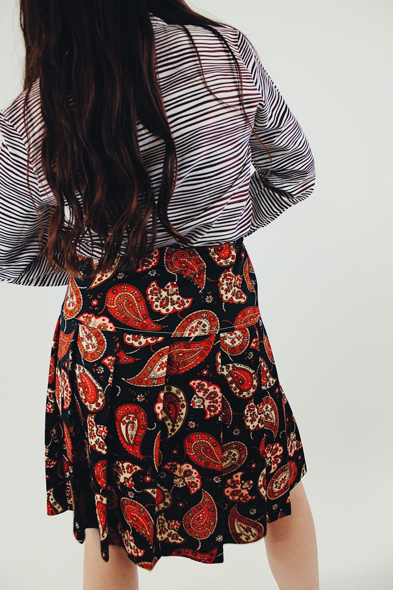 Knee length pleated skirt in forest green, red, and white paisley print back