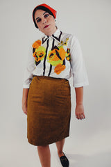 Vintage white button up blouse with green and orange flower print front tucked into skirt