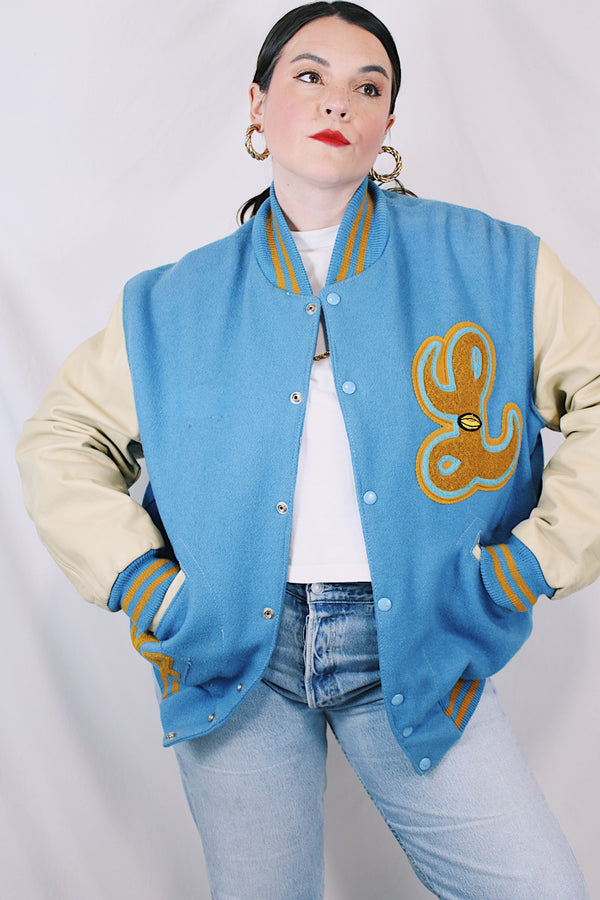 Men's or women's vintage 1994 Settlemien's, Portland, Oregon label long sleeve baby blue and cream varsity letterman jacket with yellow trim in leather and wool material. 