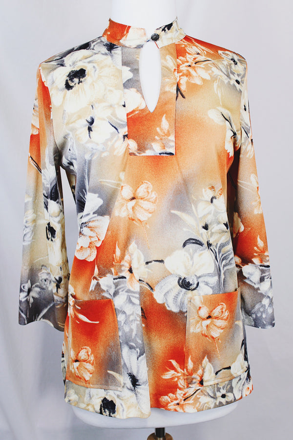 Women's vintage 1970's Pykettes label long sleeve floral printed tunic blouse with keyhole cut out front closure in grey, orange, and cream colors.