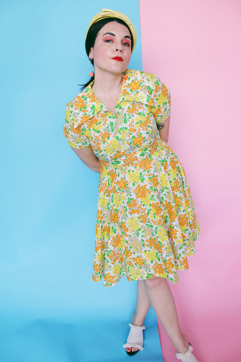 Women's vintage 1960's short sleeve polyester material mini length dress with all over green, orange, and yellow floral print.