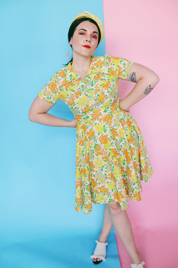 Women's vintage 1960's short sleeve polyester material mini length dress with all over green, orange, and yellow floral print.
