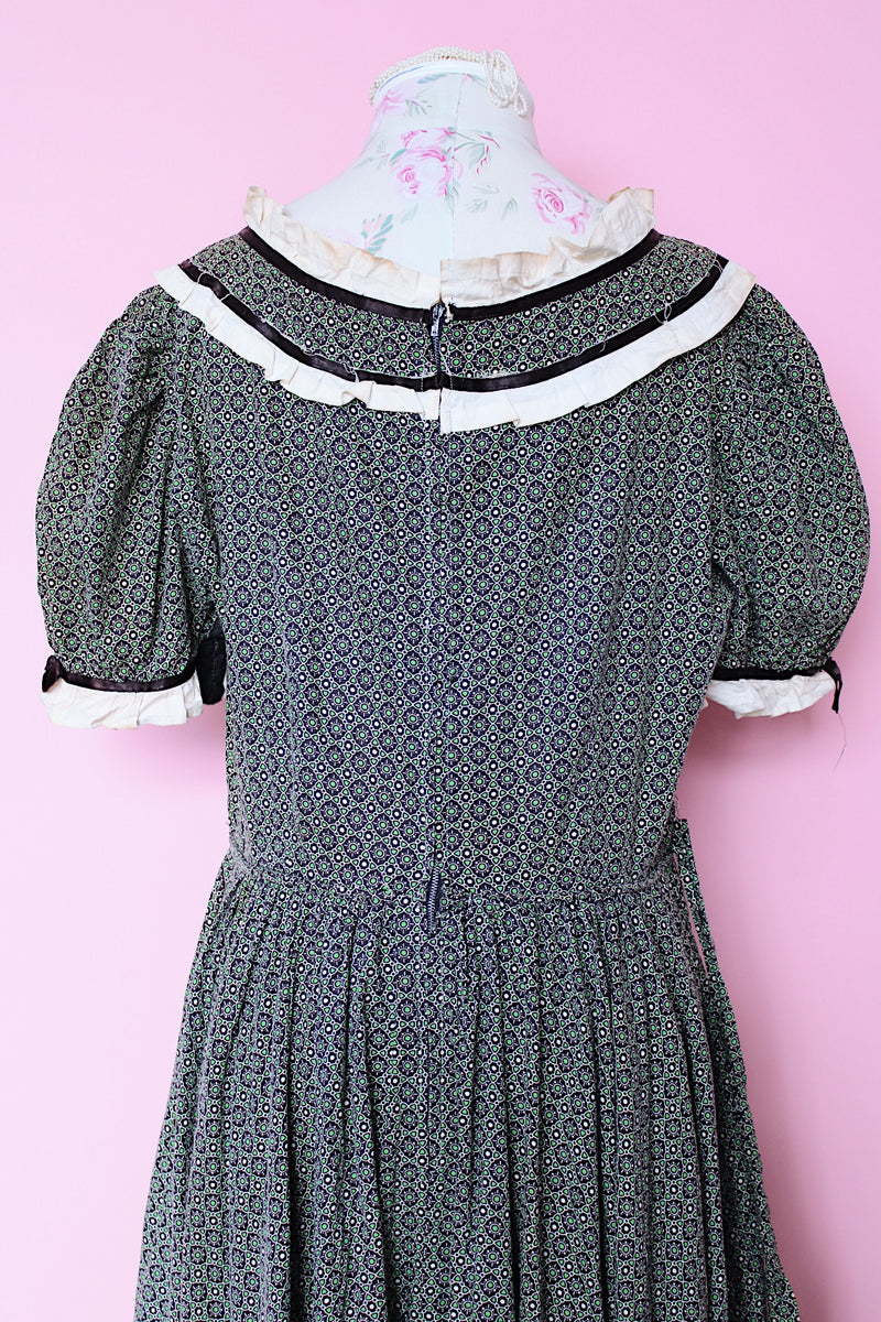 Women's vintage 1940's short sleeve maxi length cotton material prairie style dress with white and black ribbon trim around neckline and cuffs. Scalloped hem.
