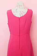 Women's vintage 1960's sleeveless mini length babydoll dress in bright pink with V shaped neckline and bow on chest.