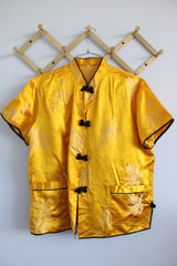 Women's vintage 1960's short sleeve gold yellow stain button up blouse with black trim and black fabric buttons.