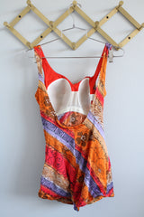 Women's vintage 1970's Sirena label sleeveless one piece swimsuit with all over orange, red, and purple print.