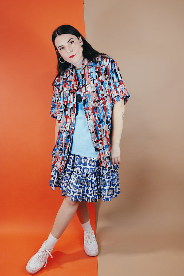 Men's or women's vintage 1970's Joel California label short sleeve button up shirt with a pointy collar. Lightweight polyester material in blue, grey, black, and salmon colored abstract print. 