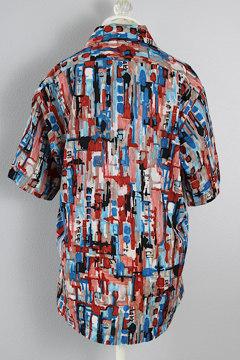 Men's or women's vintage 1970's Joel California label short sleeve button up shirt with a pointy collar. Lightweight polyester material in blue, grey, black, and salmon colored abstract print. 