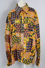 Men's vintage 1970's SKYR label long sleeve button up shirt with a pointy collar in a orange, yellow, and navy patchwork floral print in a lightweight Nylon material.
