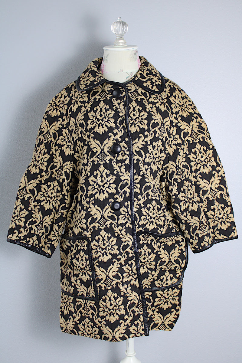 Women's vintage 1960's black and tan tapestry printed button up coat with black leather trim, two front pockets, and a rounded peter pan collar