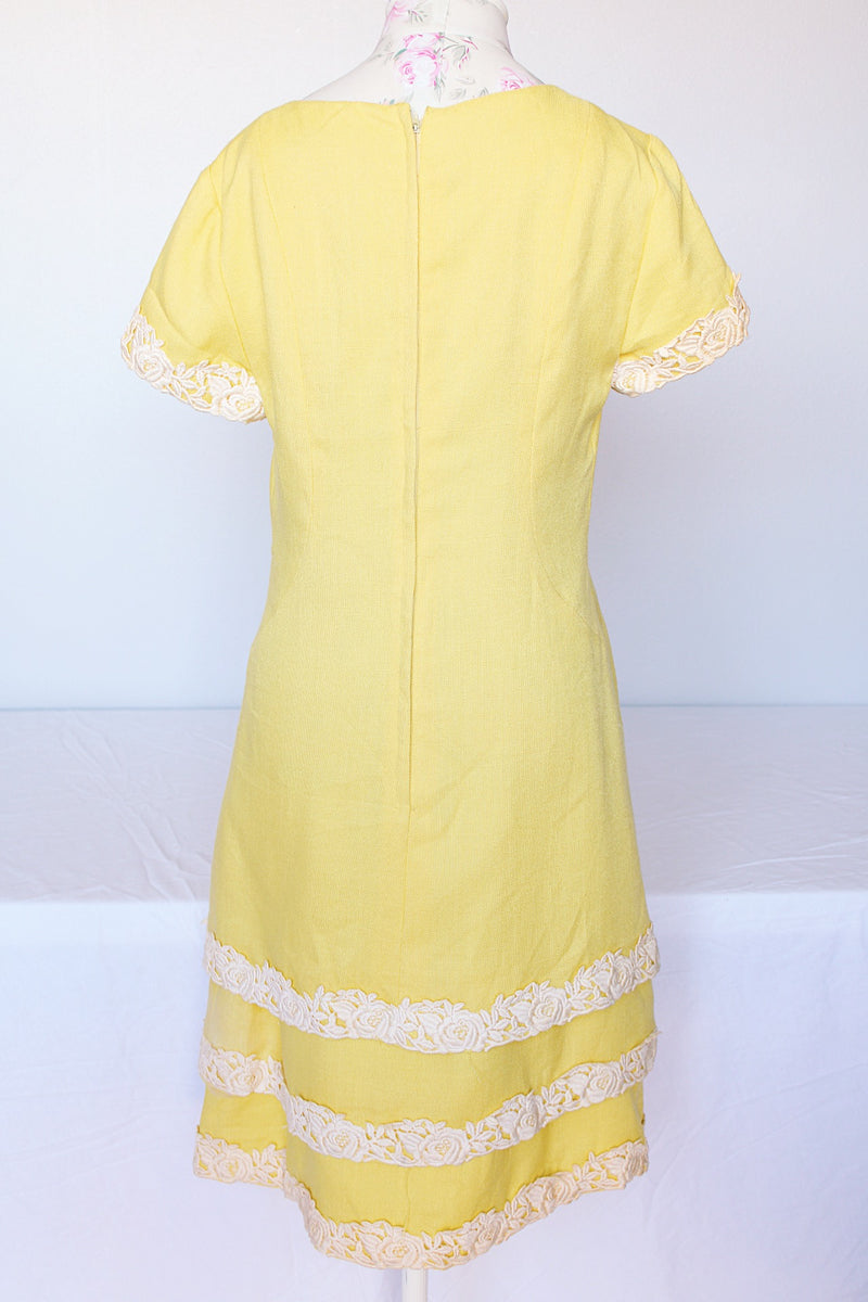Women's vintage 1960's Miss Elliette California label short sleeve knee length yellow dress with scoop neck and cream floral applique trim.