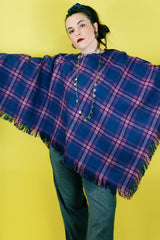 Women's vintage 1970's one size fits most navy and purple plaid print poncho with fringe hem trim and button closure on shoulder in acrylic material.