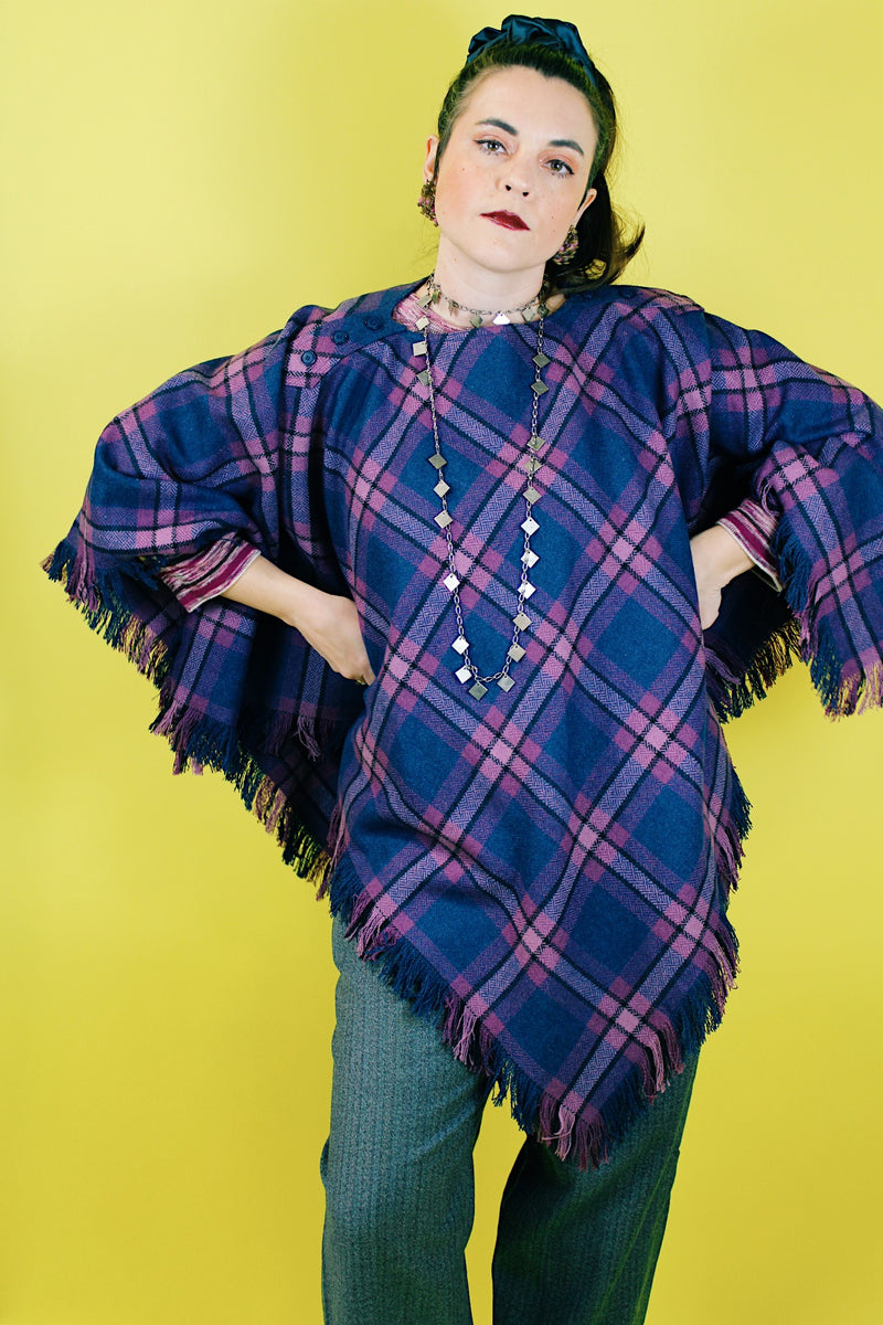 Women's vintage 1970's one size fits most navy and purple plaid print poncho with fringe hem trim and button closure on shoulder in acrylic material.