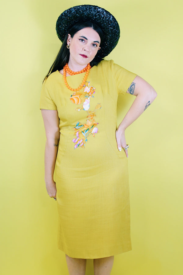 Women's vintage 1960's Jan Sue label short sleeve knee length shift dress in yellow cotton with multicolored floral print stitched on the front.
