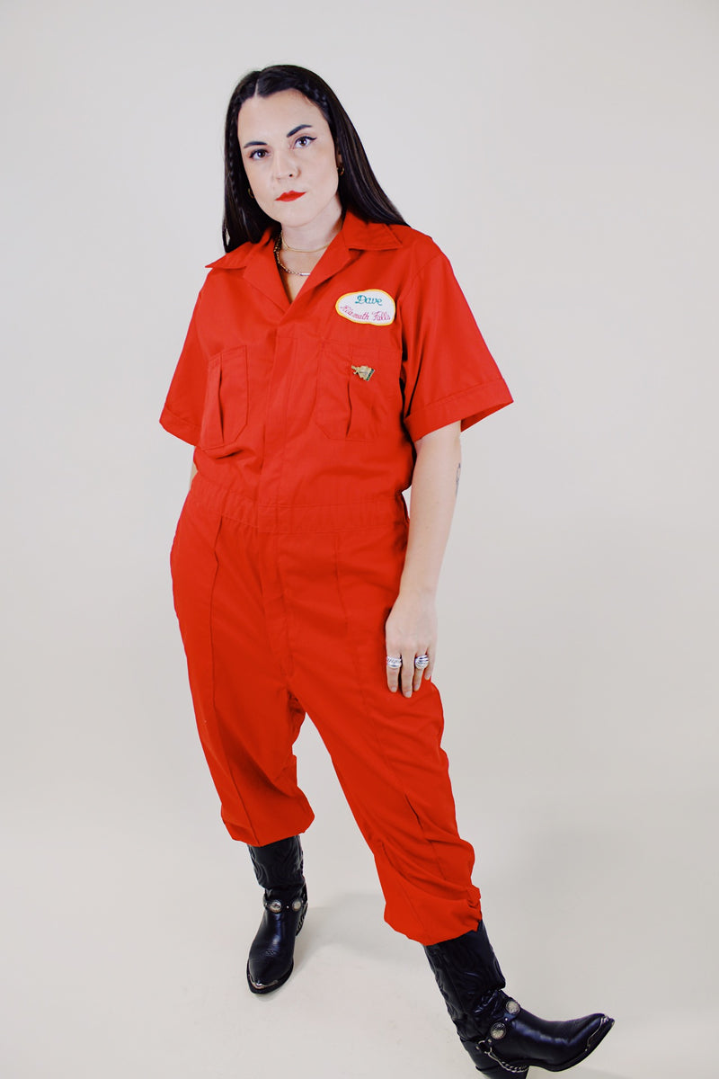 short sleeve red work jumpsuit with collar zips up front and patches on front and back vintage 1970's