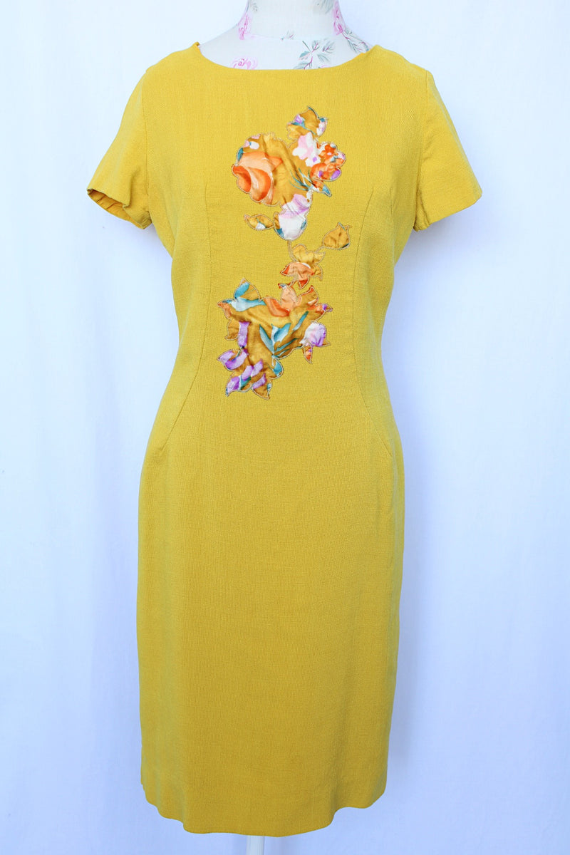 Women's vintage 1960's Jan Sue label short sleeve knee length shift dress in yellow cotton with multicolored floral print stitched on the front.