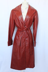 Women's vintage 1970's long length long sleeve leather wrap coat in maroon color. Double lapel, tie belt, pockets.