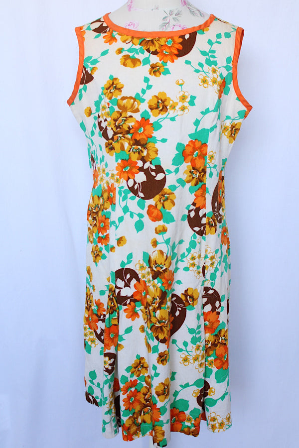 Women's vintage 1960's sleeveless knee length shift dress in off white with an all over floral print and orange trim.