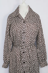 Women's vintage 1970's long sleeve knee length button up shirt dress in brown with all over white floral print. 