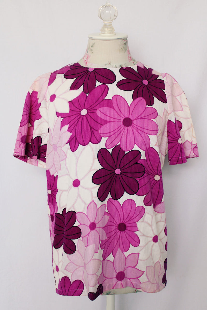 Women's vintage 1960's short sleeve floral print cotton blouse with one button closure in the back. White with purple flowers.