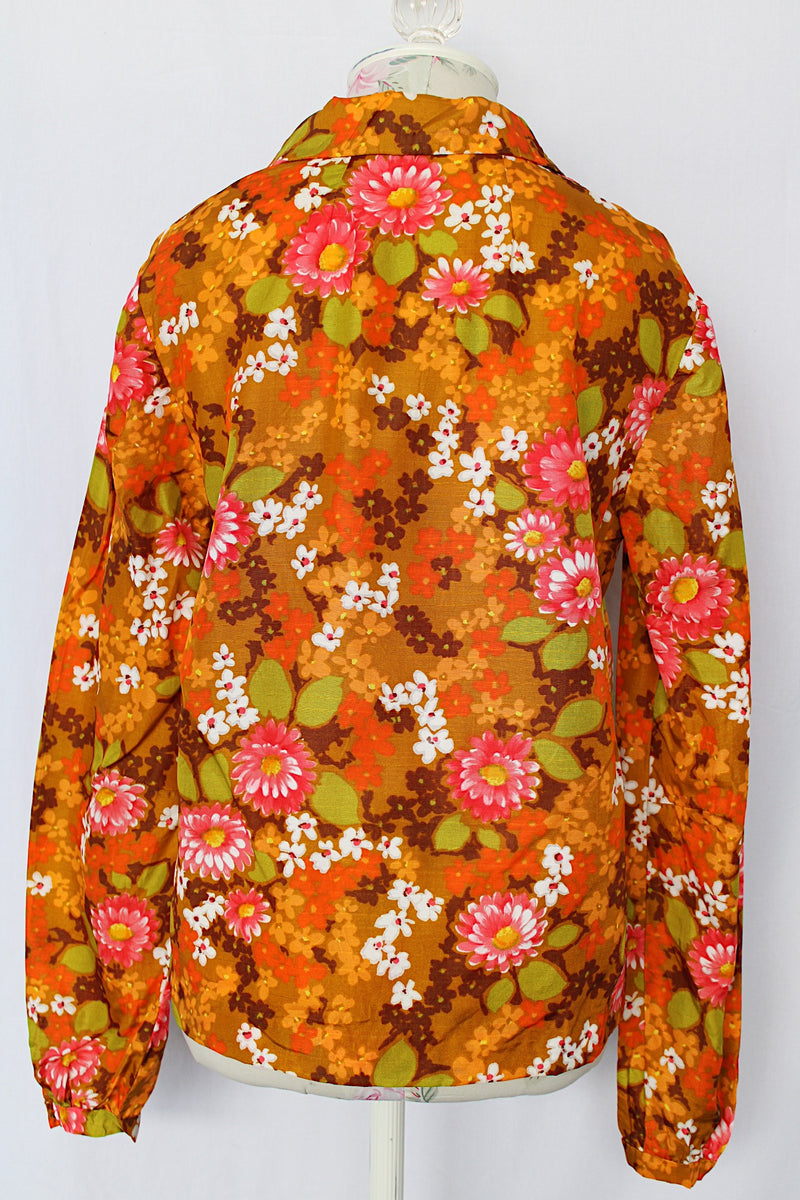 Women's vintage 1970's long sleeve floral printed blouse with half zipper closure and pointy dagger collar. Floral print is in shades of brown and orange
