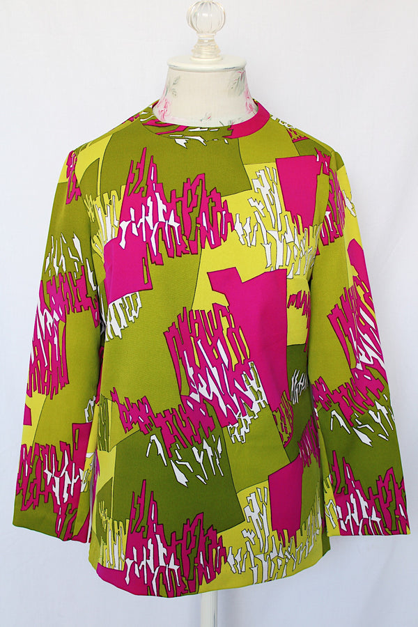 Women's vintage 1970's long sleeve polyester blouse with zipper in the back and darted bust. All over green and purple print