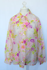 Women's vintage 1970's long sleeve button up blouse with pointy dagger collar. White sheer polyester with all over purple and pink floral print.