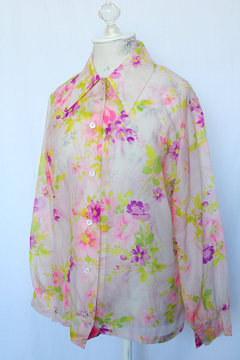 Women's vintage 1970's long sleeve button up blouse with pointy dagger collar. White sheer polyester with all over purple and pink floral print.