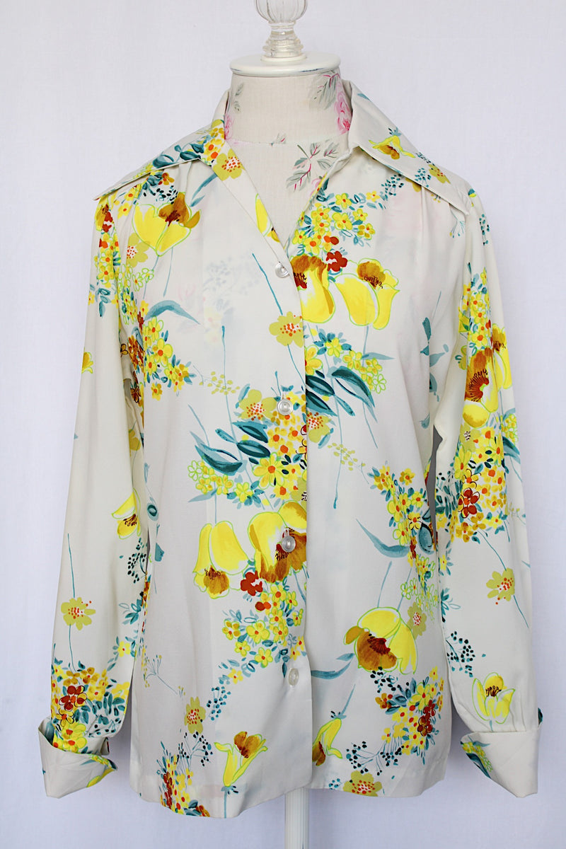 Women's vintage 1970's Hollywood Blouse by Praw, Made in California label long sleeve button up blouse with collar in white polyester with all over yellow and blue floral print.