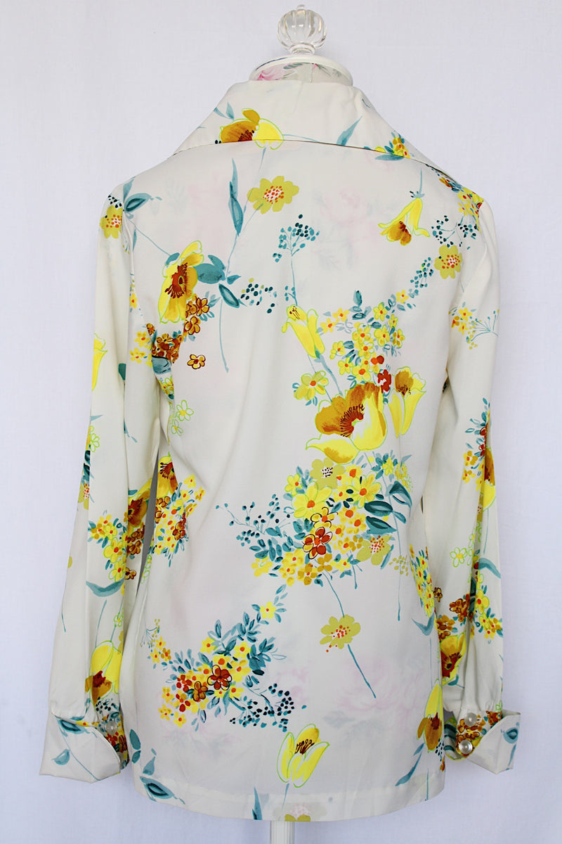 Women's vintage 1970's Hollywood Blouse by Praw, Made in California label long sleeve button up blouse with collar in white polyester with all over yellow and blue floral print.
