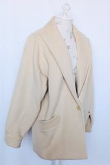 Women's vintage 1980's long sleeve short cream colored wool coat with a one button closure.