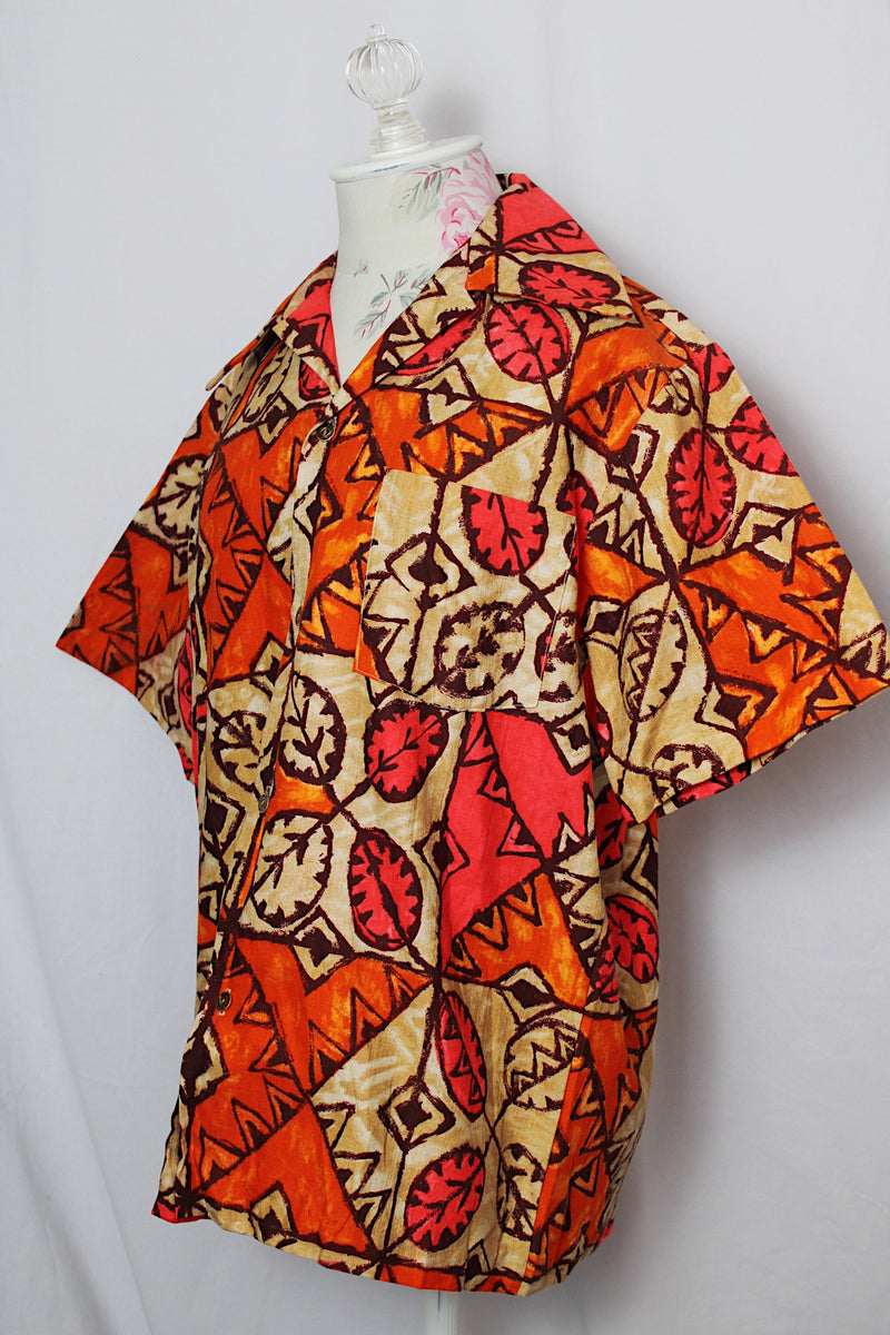 Women's or men's vintage 1960's made in Hawaii short sleeve button up shirt with pointy collar in cotton material with all over tan, orange, and pink Hawaiian print. 