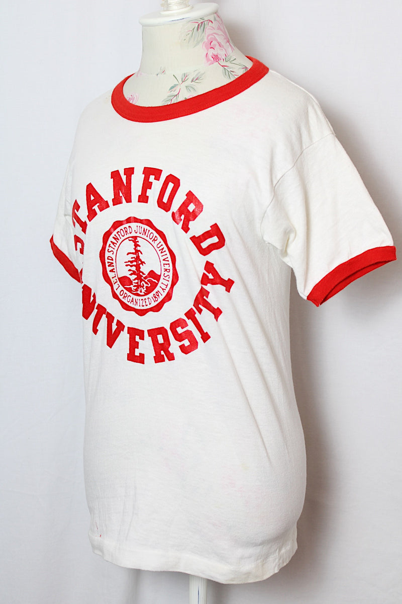 Women's or men's vintage 1970' Champion label short sleeve white tee with red trim around cuffs and neck. Stanford University graphic on the front.