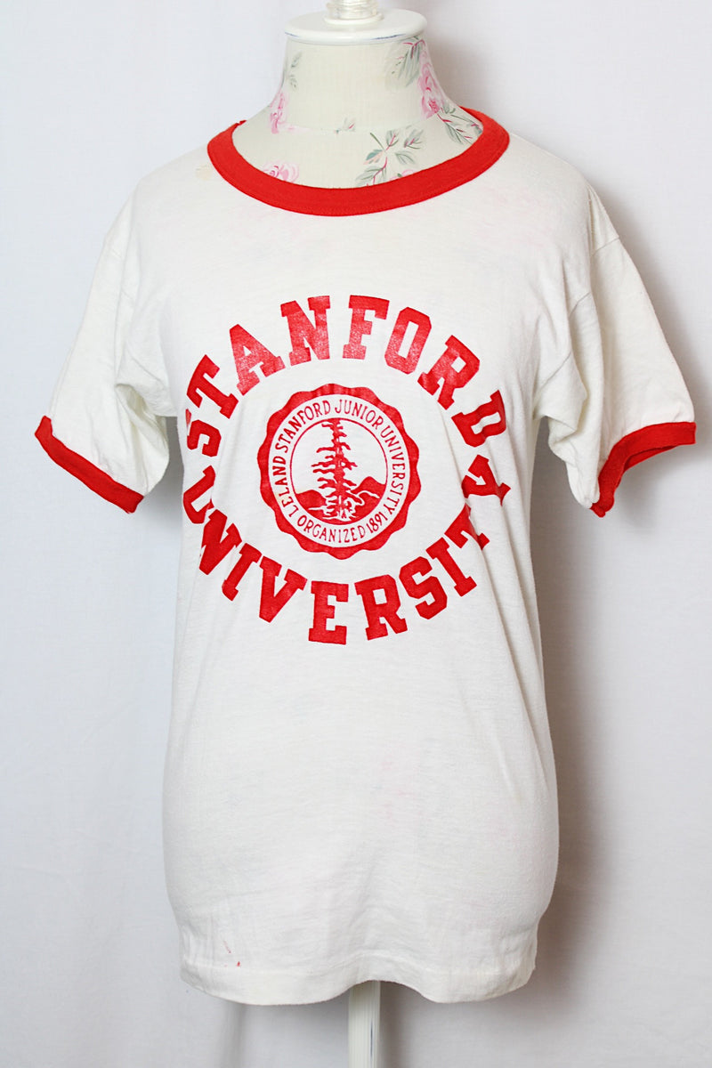 Women's or men's vintage 1970' Champion label short sleeve white tee with red trim around cuffs and neck. Stanford University graphic on the front.