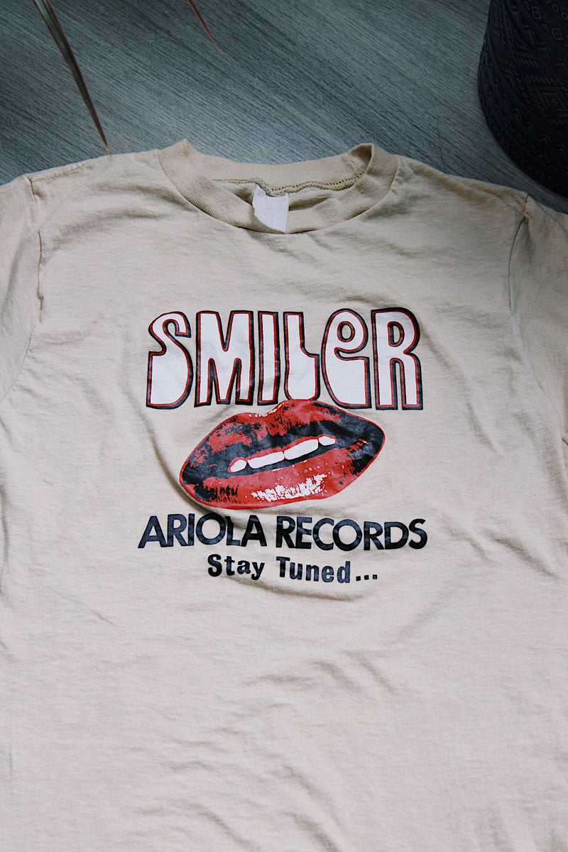 short sleeve light tan cotton t-shirt with Smiler Ariola Records graphic on the front 1970's