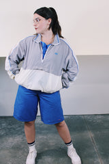 Women's or men's vintage 1980's Nike label long sleeve lightweight pullover windbreaker with a half zip closure in grey, white, and blue.