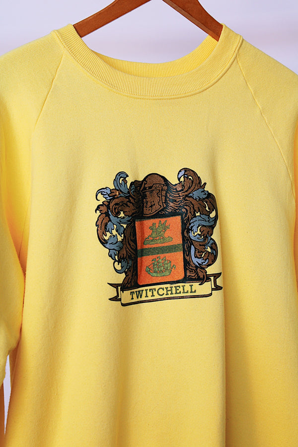 long sleeve yellow vintage crew neck sweater with emblem graphic on front