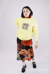 long sleeve yellow vintage crew neck sweater with emblem graphic on front