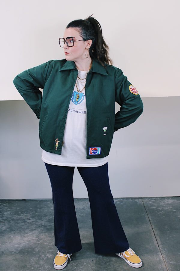 Women's or men's vintage 1980's Riverside Flexbac, Made in USA label long sleeve green zip up station jacket with patches all over. Has collar and pockets.