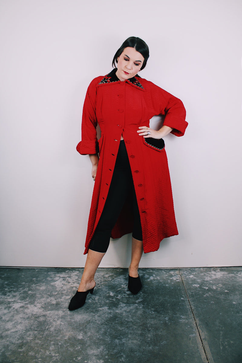 1950's red quilted duster coat with black velvet trim has pointy collar and buttons up the front