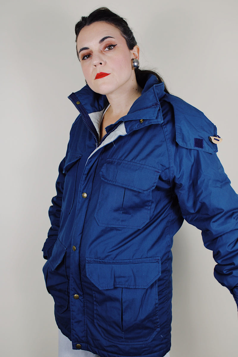 vintage 1980's Woolrich, Made in USA label long sleeve dark blue zip up parka jacket with removable hood, four front velcro pockets, and brass popper buttons
