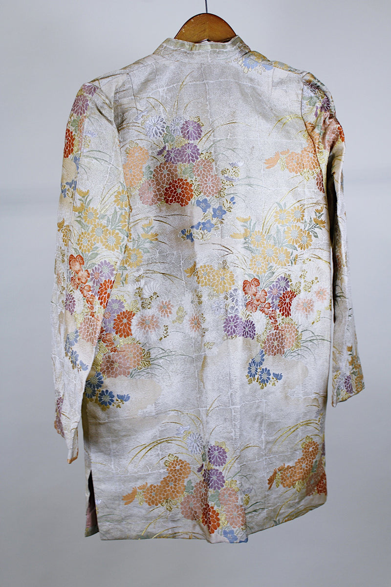 Women's vintage 1960's long sleeve and long length gold colored silk robe kimono with all over multicolored embroidered floral design. Pockets, mandarin collar and fabric covered buttons