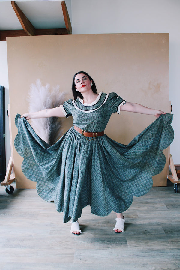 Women's vintage 1940's short sleeve maxi length cotton material prairie style dress with white and black ribbon trim around neckline and cuffs. Scalloped hem.