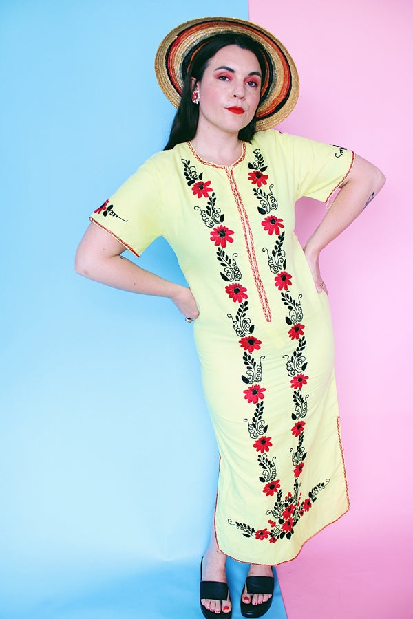 Women's vintage 1970's Wendy-Ann Inc. label short sleeve ankle length cotton material dress in bright yellow with all over red and black embroidered floral design.