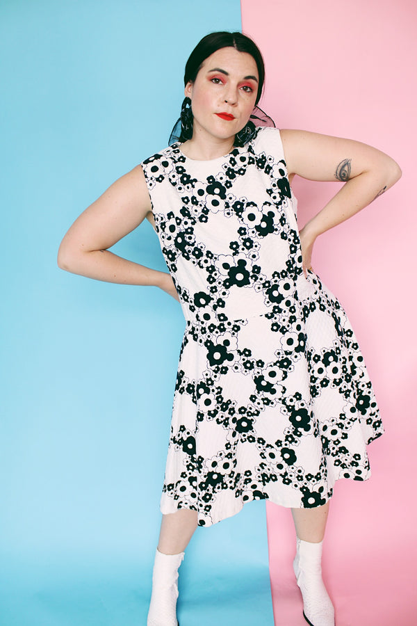 Women's vintage 1970's sleeveless drop waist midi length cotton material dress in white with all over black floral print.