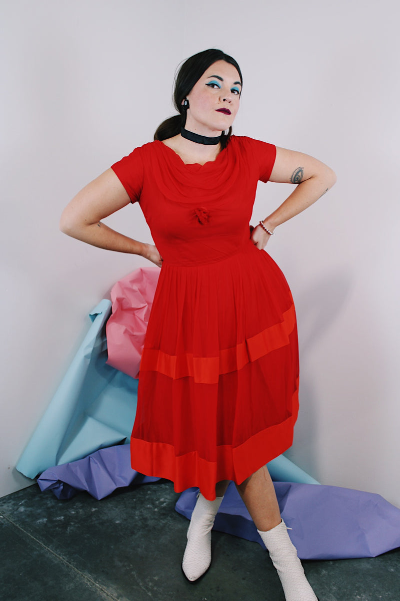Women's vintage 1960's short sleeve capped sleeve knee length midi dress in vibrant red with a scoop neckline and flower on chest.